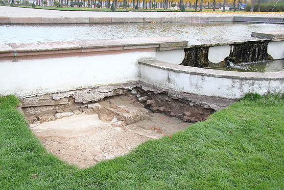 Ausschnitt der Grabung am Hirschbrunnen: links der Tuffstein-Unterbau für das Spiegelbecken mit den Resten des Estrichs, rechts die erhaltenen Stufen des Wassertischs, über den das Wasser aus dem oberen Bassin in das Spiegelbassin floss.